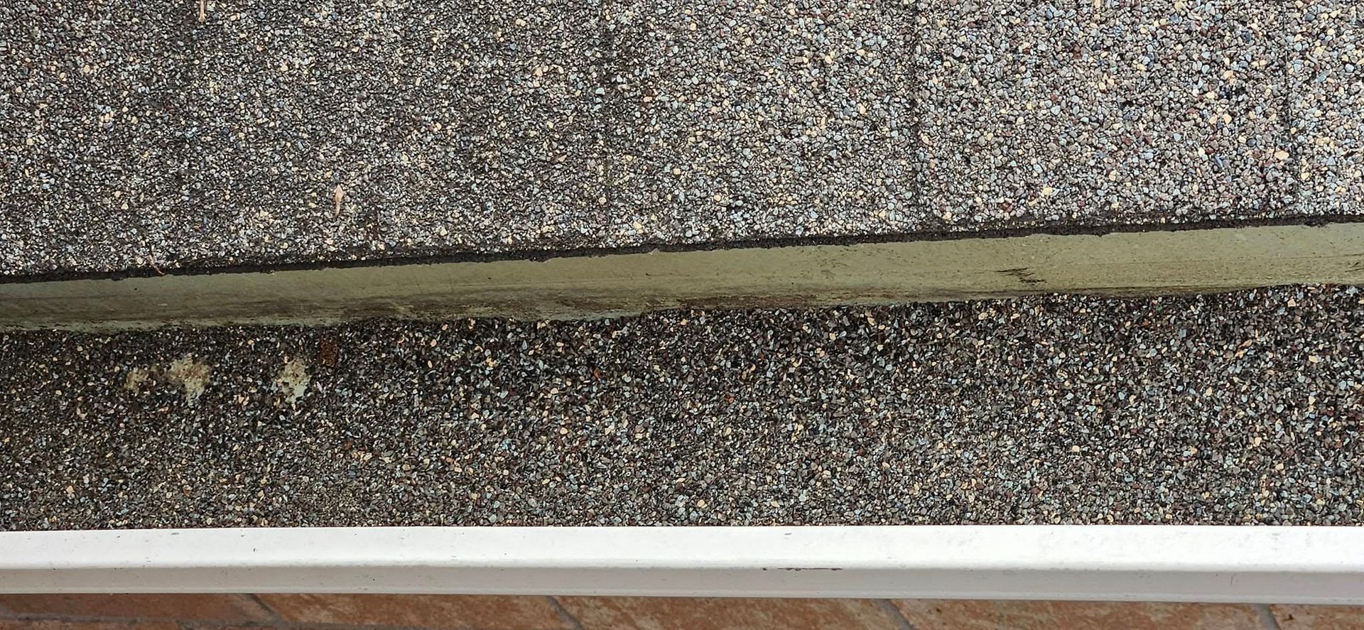 A close-up of a stair tread with a textured, dark gray speckled surface and a bright white metal nosing edge.