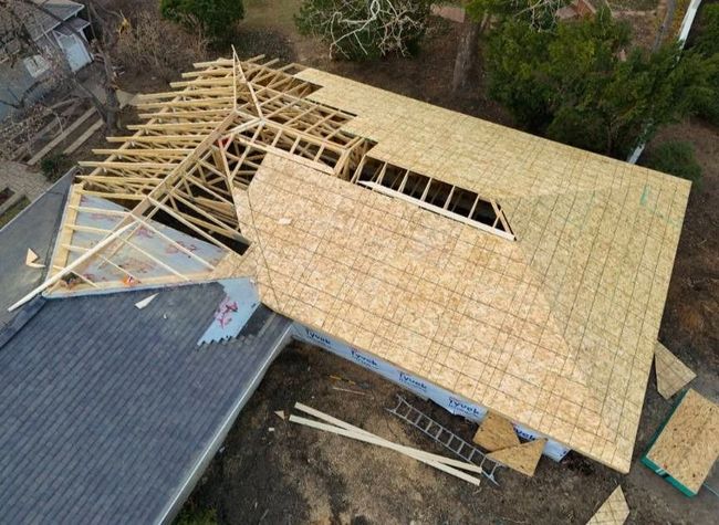 A man is standing in the middle of a wooden structure under construction.
