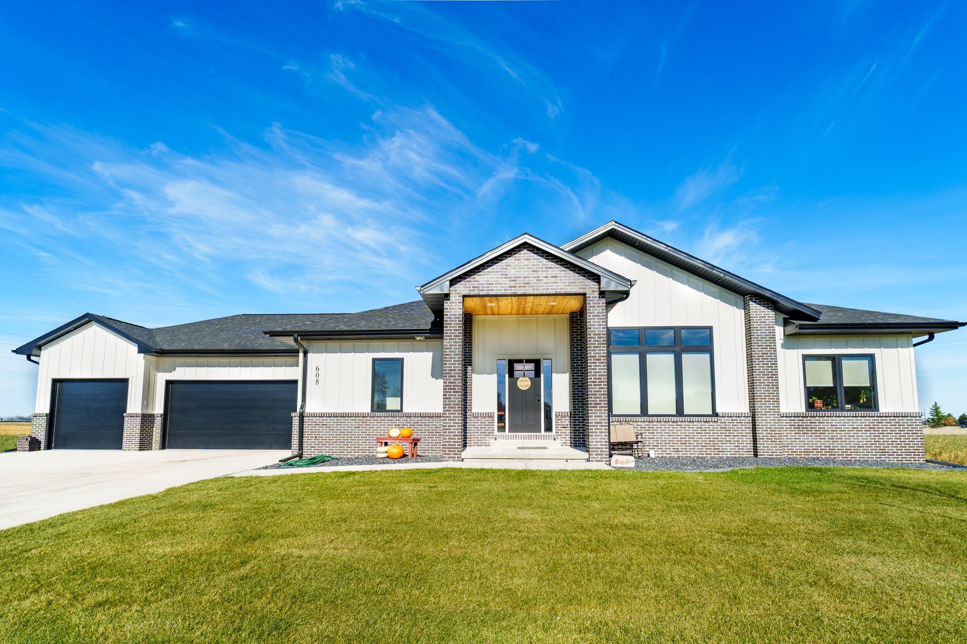 A large house with two garages and a lush green lawn in front of it.