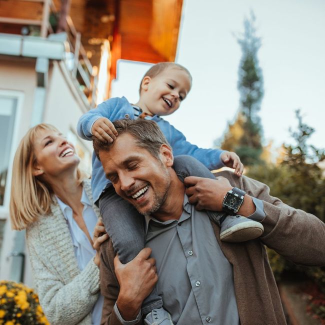 A man is carrying a little boy on his shoulders.