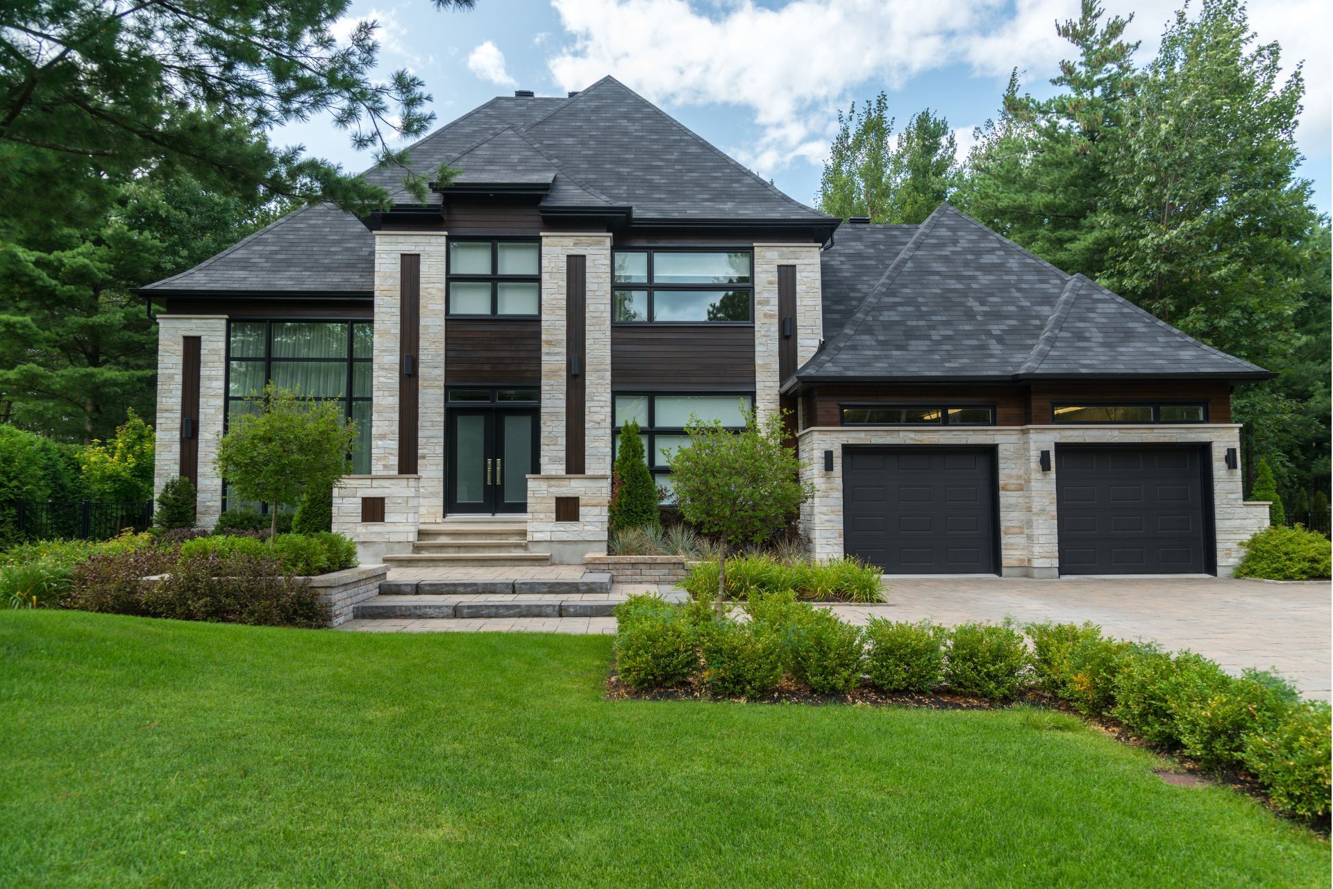 A large house with two garages and a lush green lawn in front of it.