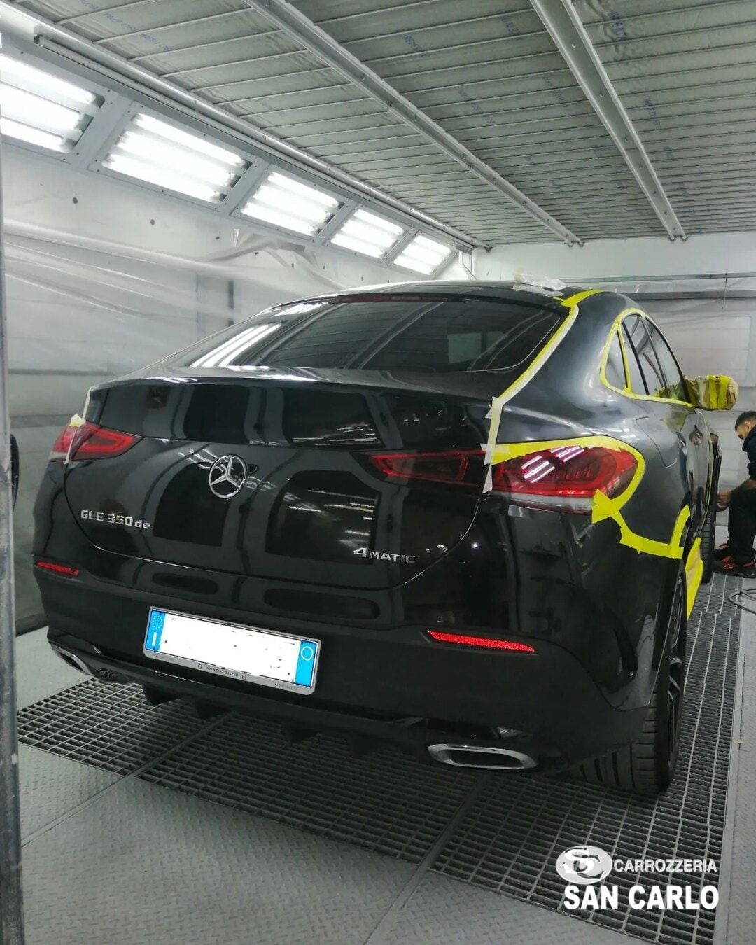Toyota SUV nera avvolta con nastro giallo in un autolavaggio al coperto, vista posteriore