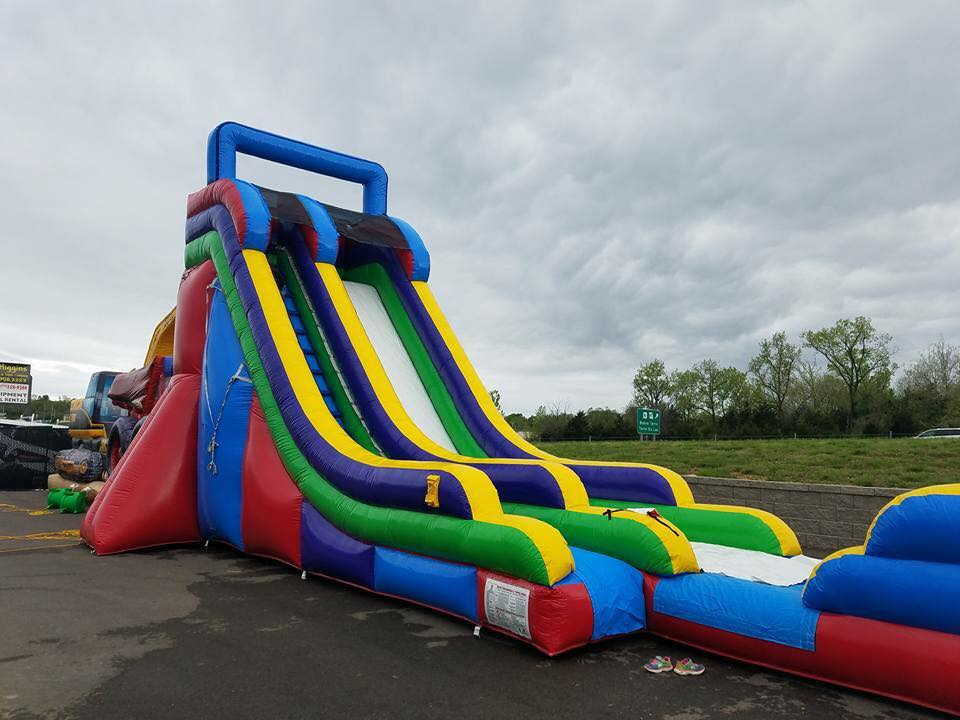 Colorful inflatable obstacle slide on a wet outdoor pavement under a cloudy sky