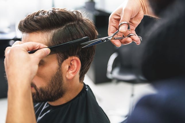 Barber trimming a man's hair with scissors in a salon