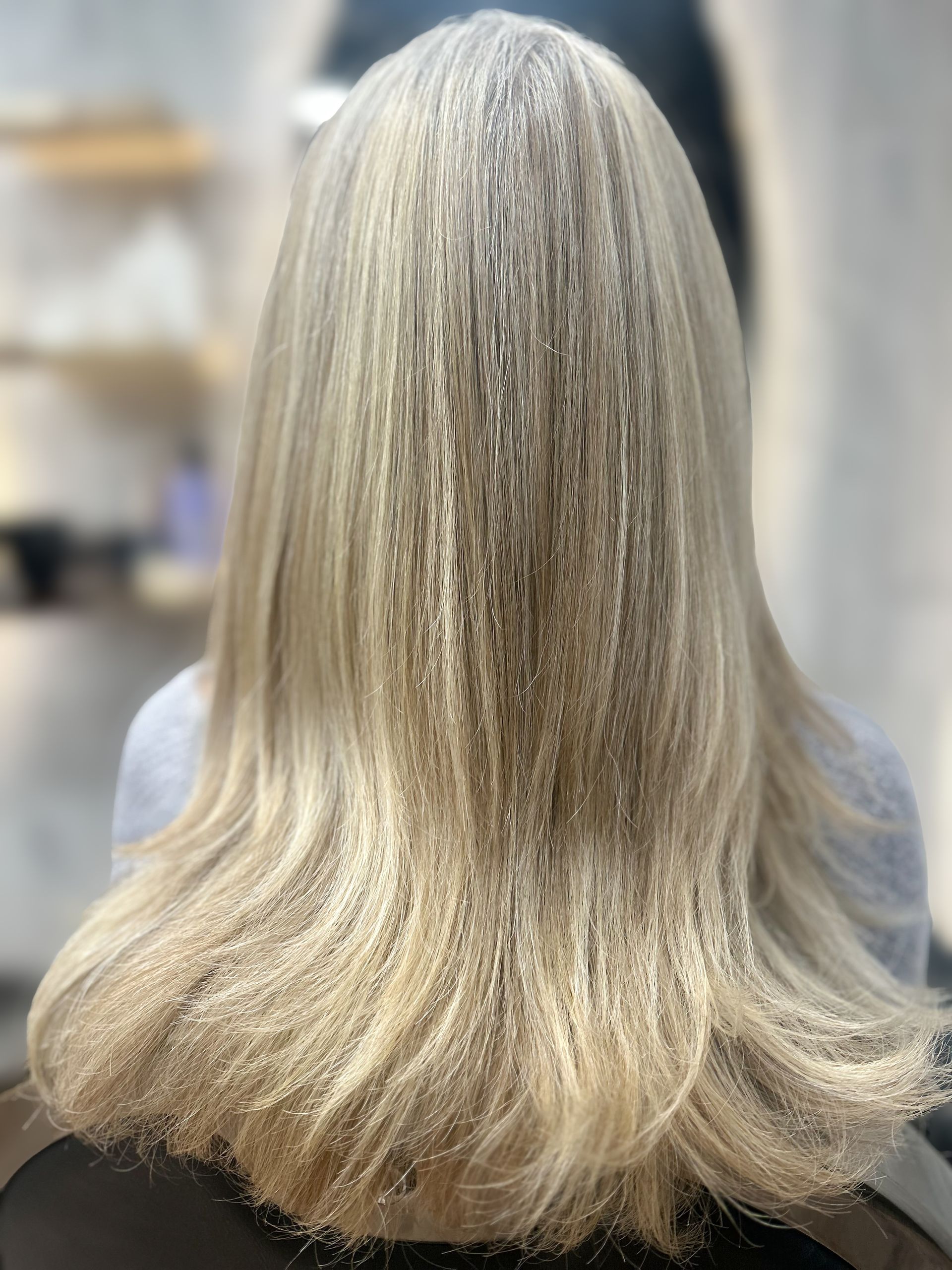 Back view of shoulder-length silver-blonde hair with soft waves in a salon setting