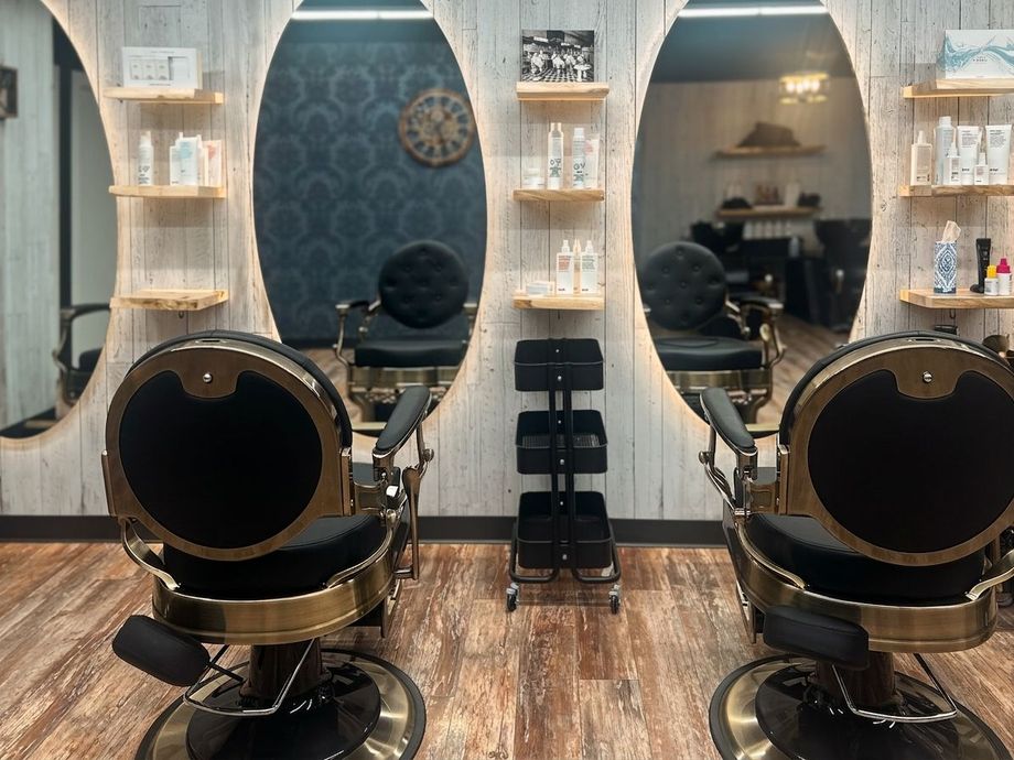 Modern salon interior with two black styling chairs facing mirrors and shelves of hair products