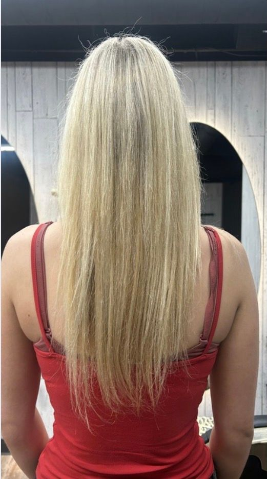 Back view of a person with long blonde hair wearing a red tank top.