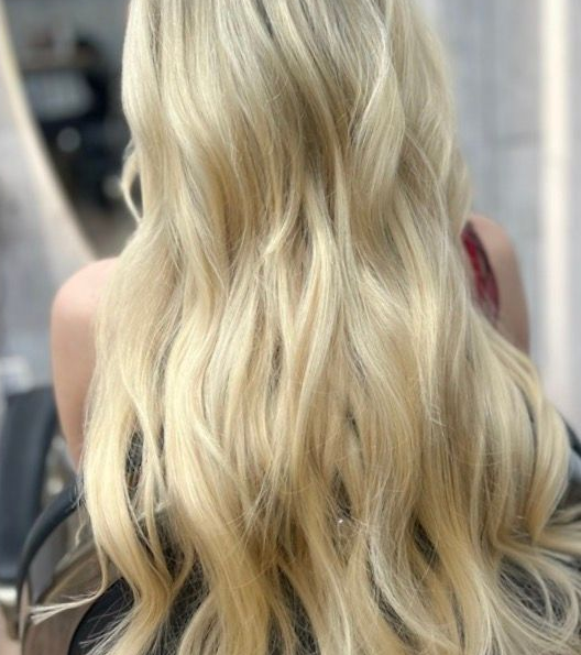 Long blonde wavy hair viewed from behind, cascading to mid-back.