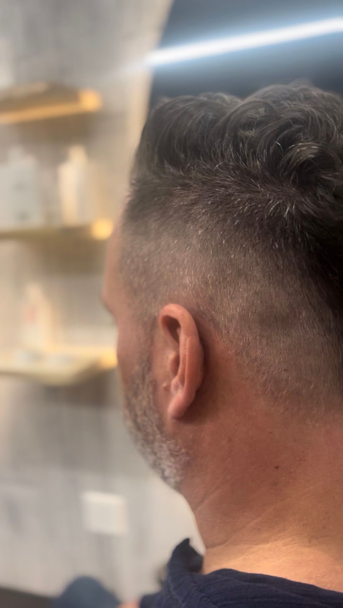 Close-up of the back of a man’s head with a short fade haircut in a barbershop.