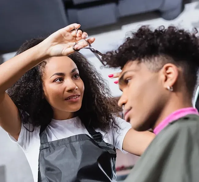Hair stylist adjusting a client’s curly hair in a salon chair