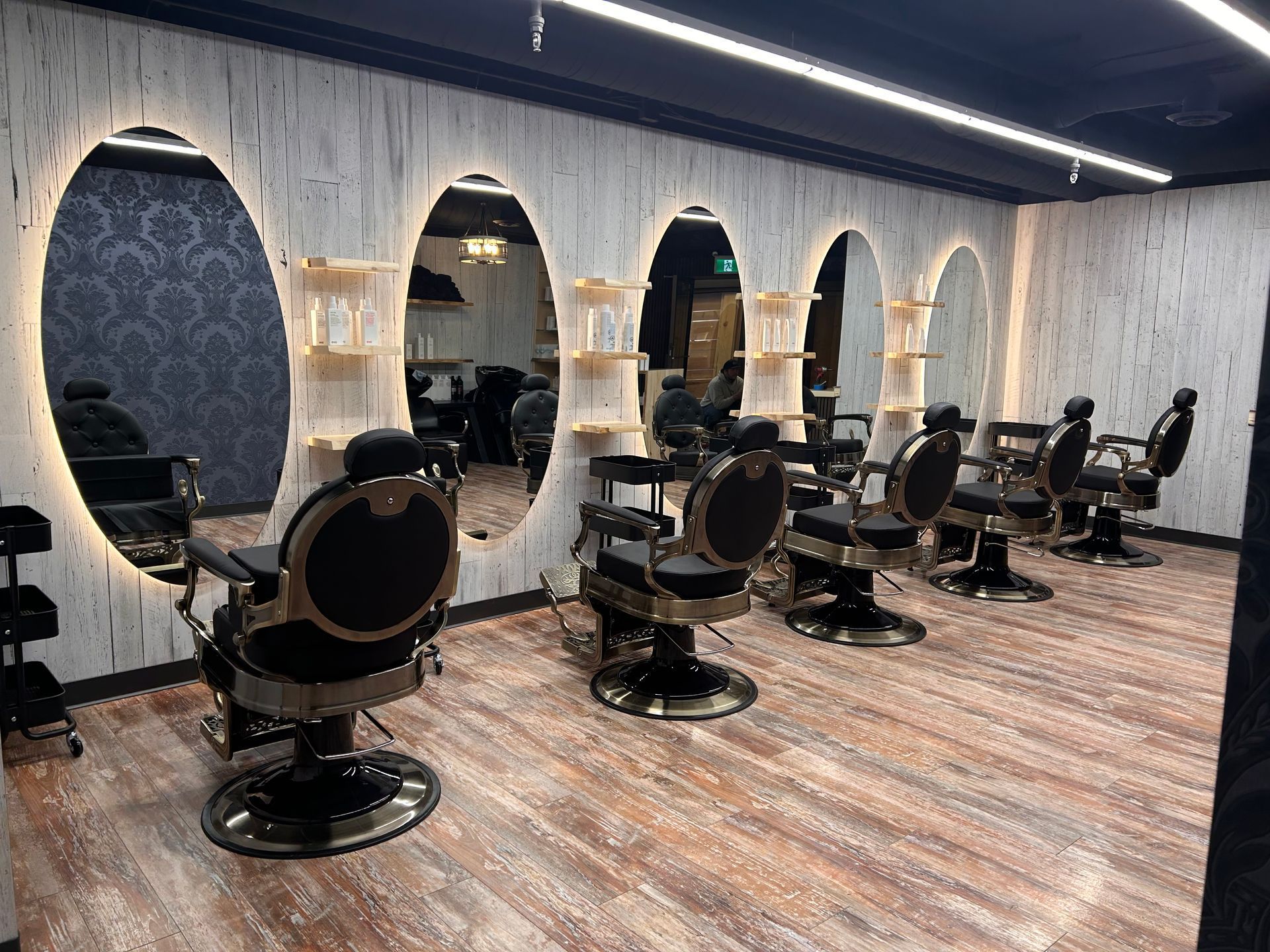 Empty modern barbershop with black styling chairs, mirrors, and patterned walls