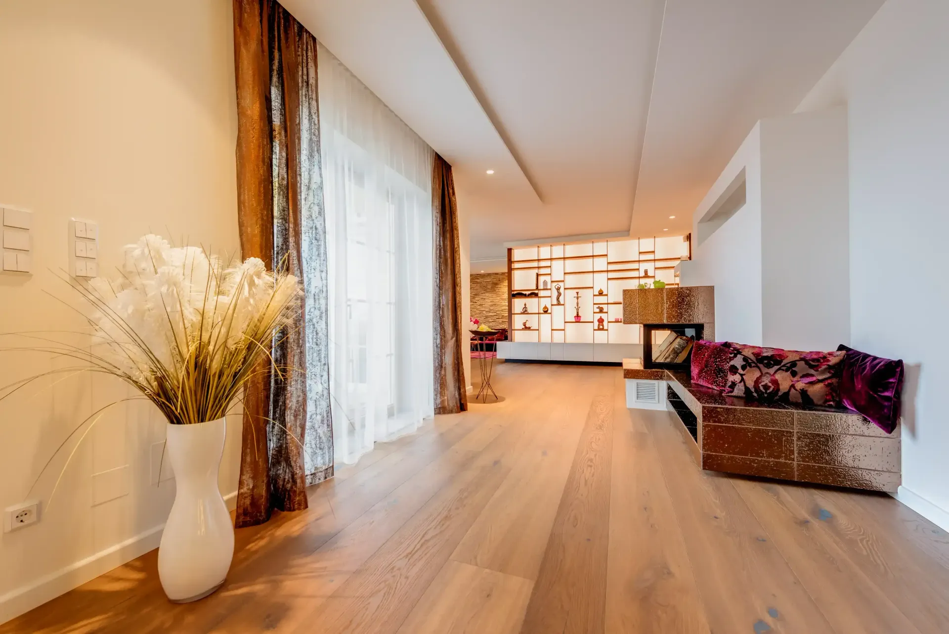 Modernes Interieur mit Hartholzböden, dekorativen Blumen, gemusterten Vorhängen und einer dekorativen Wand.