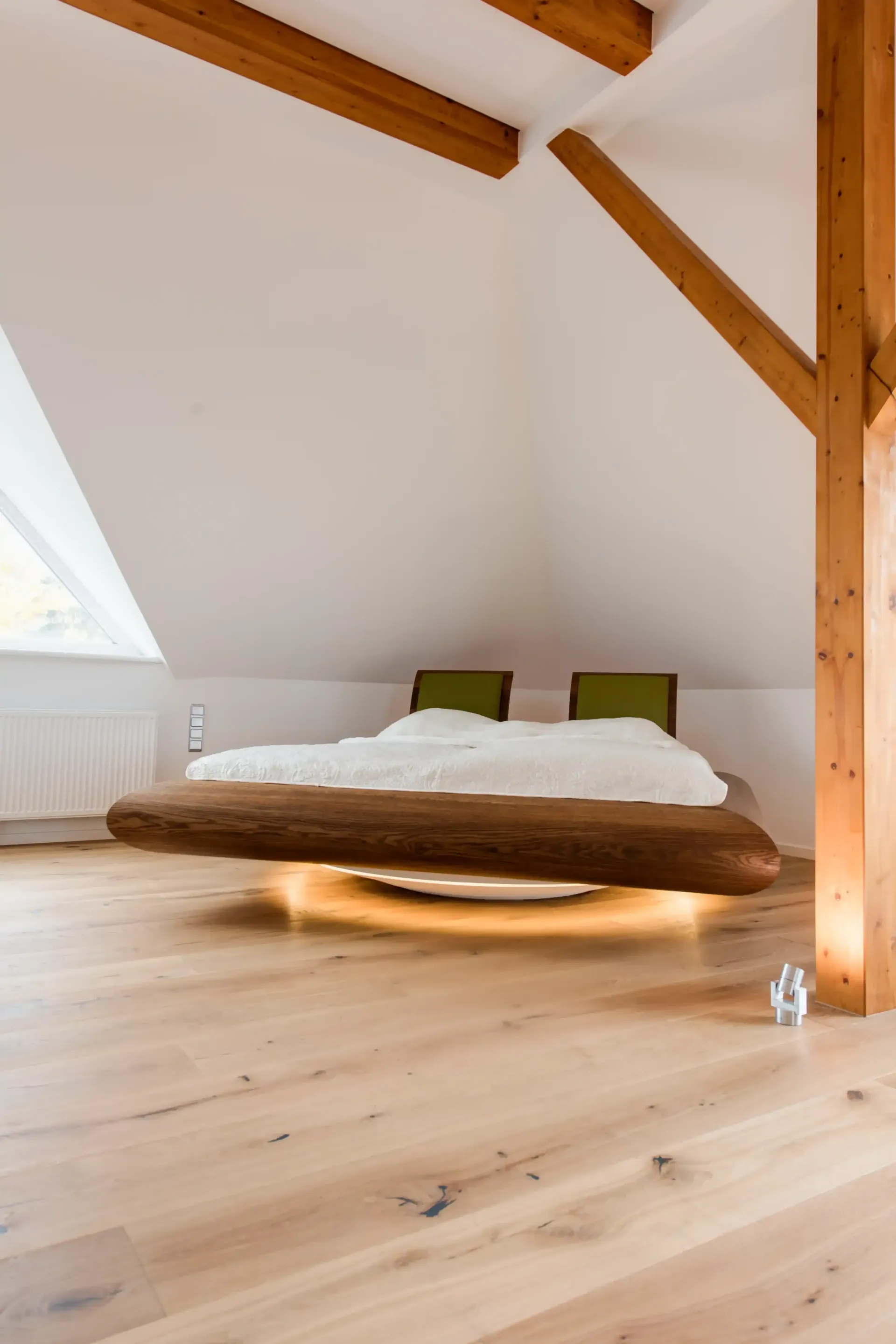 Ein schwebendes Bett in einem lichtdurchfluteten Raum mit Holzbalken und Holzboden.
