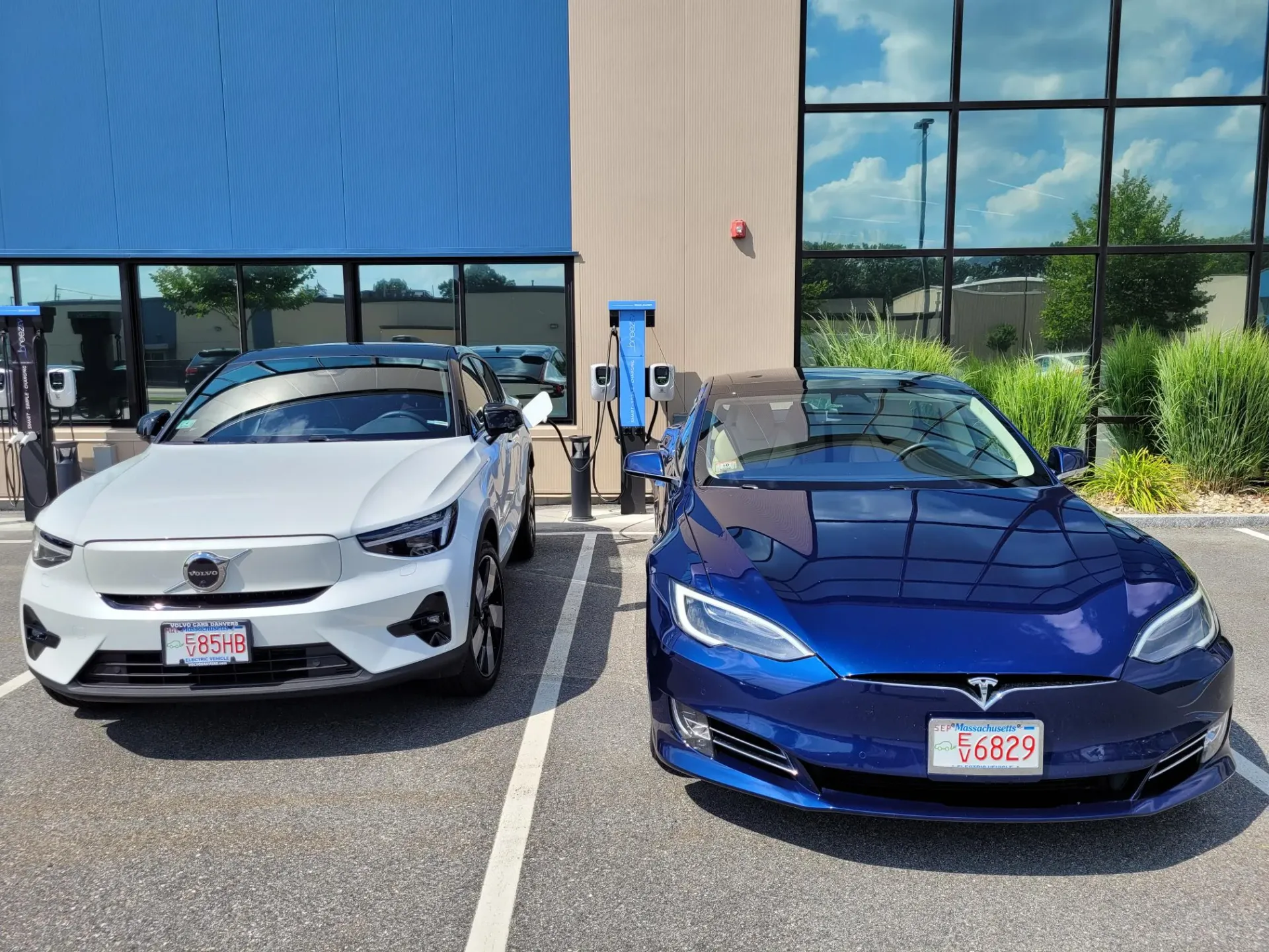 Two electric cars are parked next to each other in a parking lot.