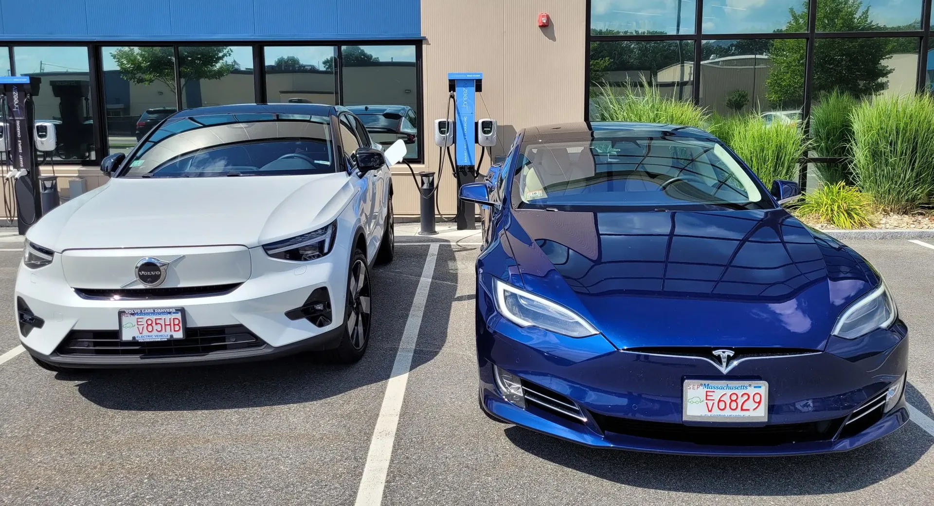 Two electric cars are parked next to each other in a parking lot.