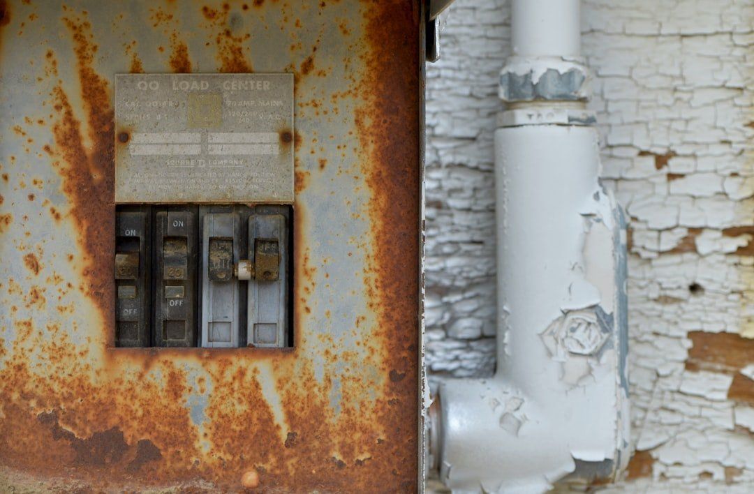 A close up of a rusty electrical box on a wall.