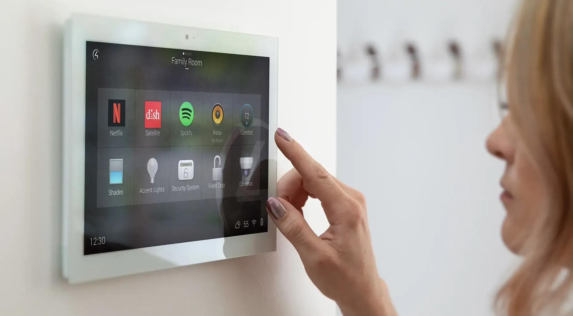 A woman is using a tablet to control a smart home system.