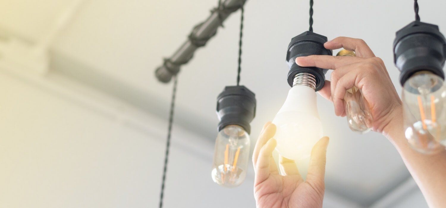 A person is changing a light bulb on a ceiling.