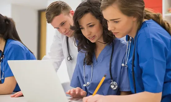 Um grupo de estudantes de medicina está olhando para um laptop.