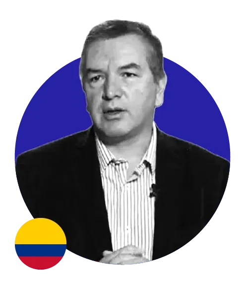 Um homem de terno está em pé em frente a um círculo azul com uma bandeira da Colômbia ao fundo.