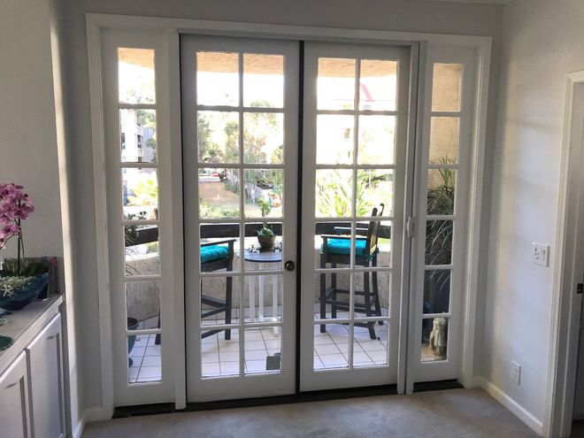 Bright French doors opening to a patio with turquoise chairs and a small table outside