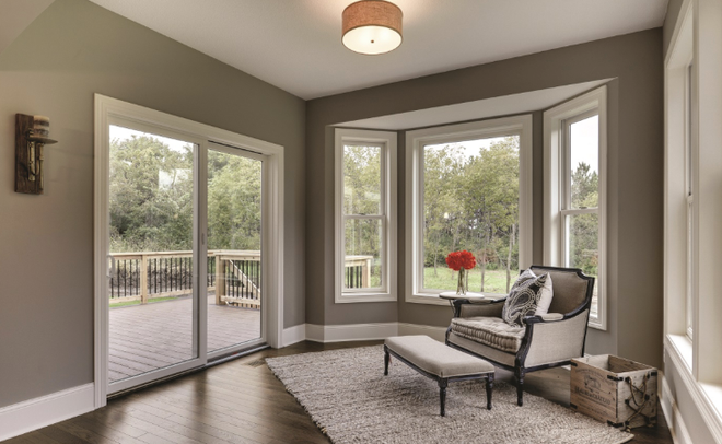 Front view of a screened porch door on a shingled house, flanked by narrow windows.