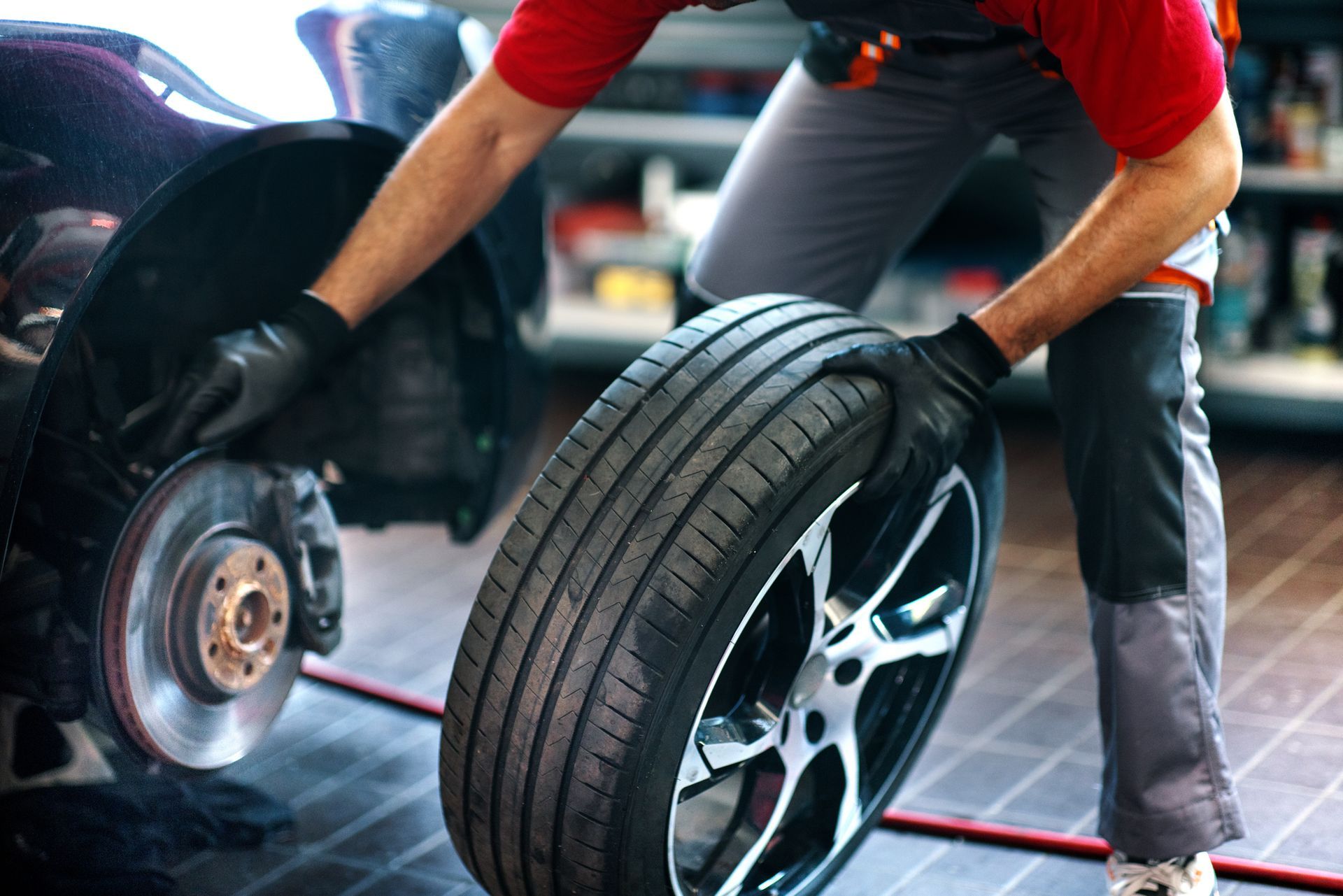 Mechanic in a garage changing a tire on a black car.