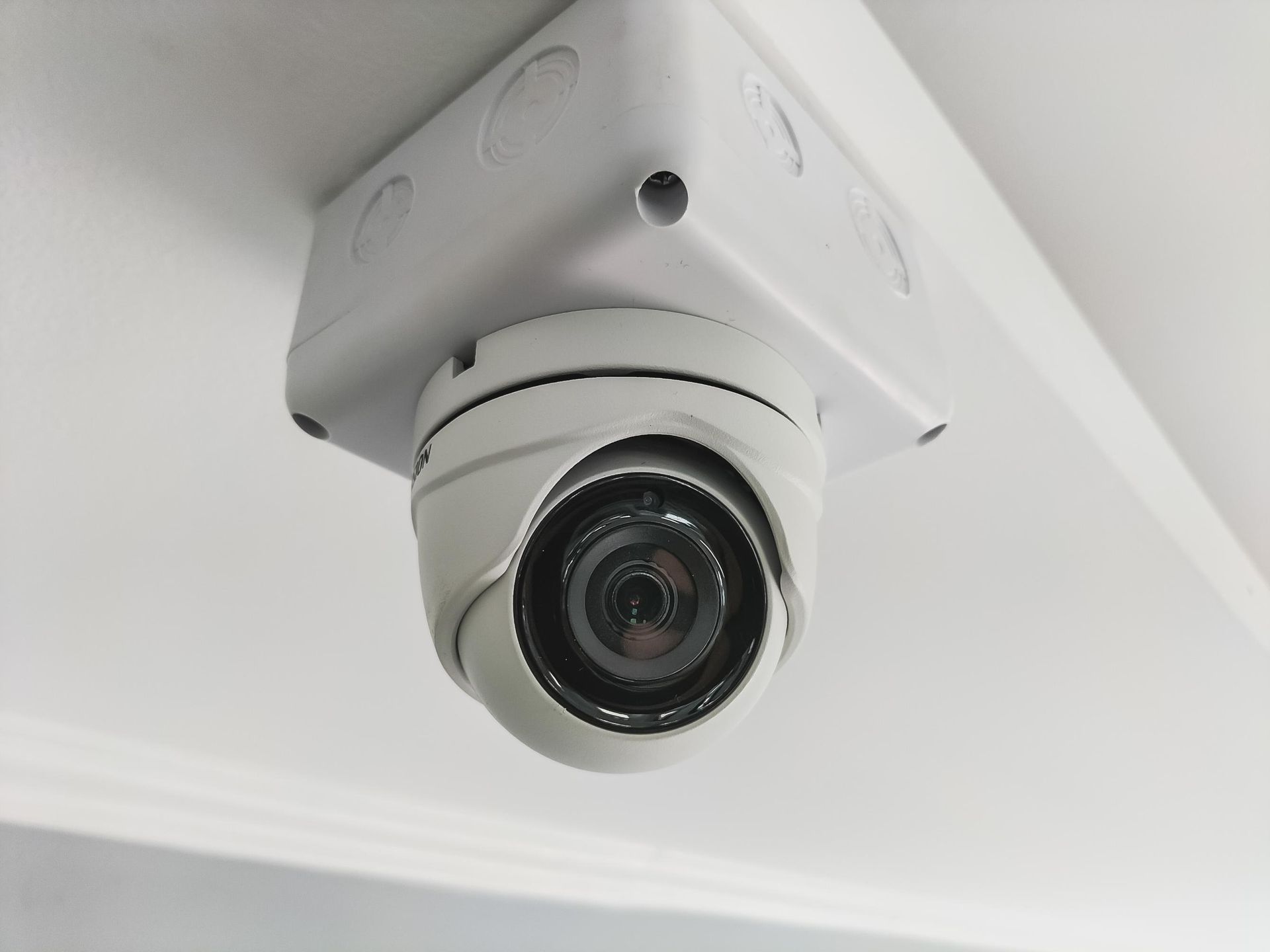 A person is installing a security camera on a wall.