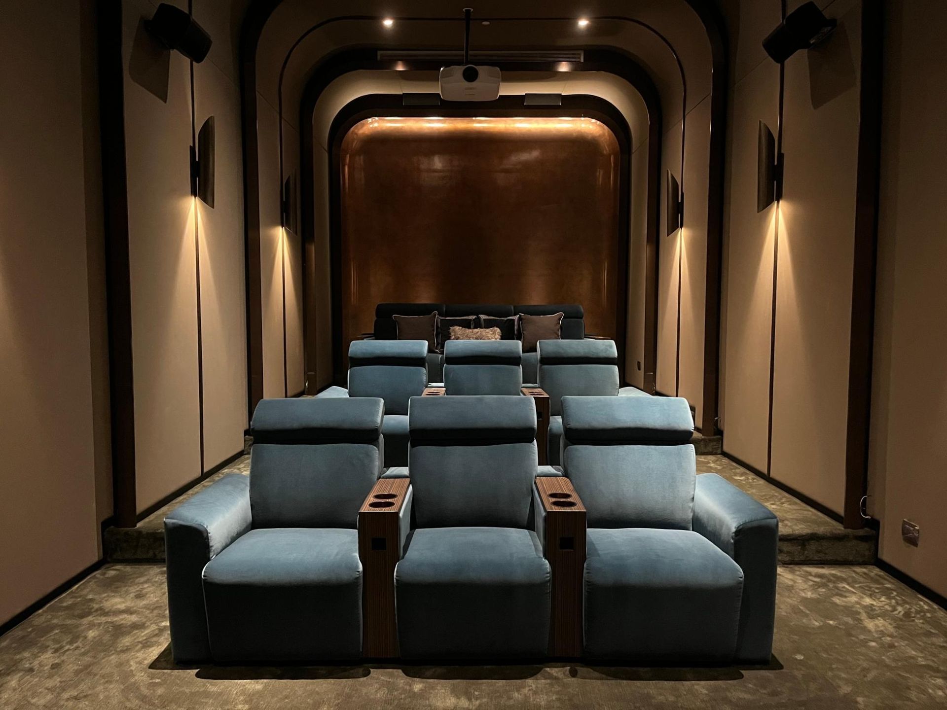 A theater with blue chairs and a projector screen.