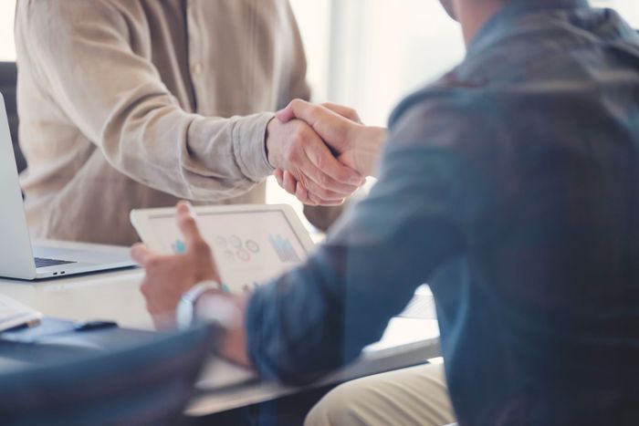Two men are shaking hands while sitting at a table. Two men are shaking hands while sitting at a table.