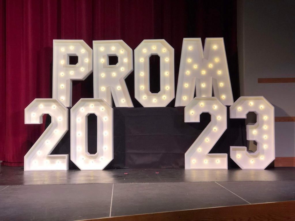 A sign that says prom 2023 is lit up on a stage