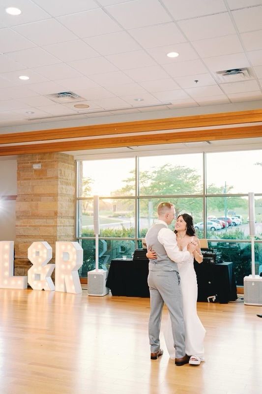 A bride and groom are dancing on a wooden dance floor.