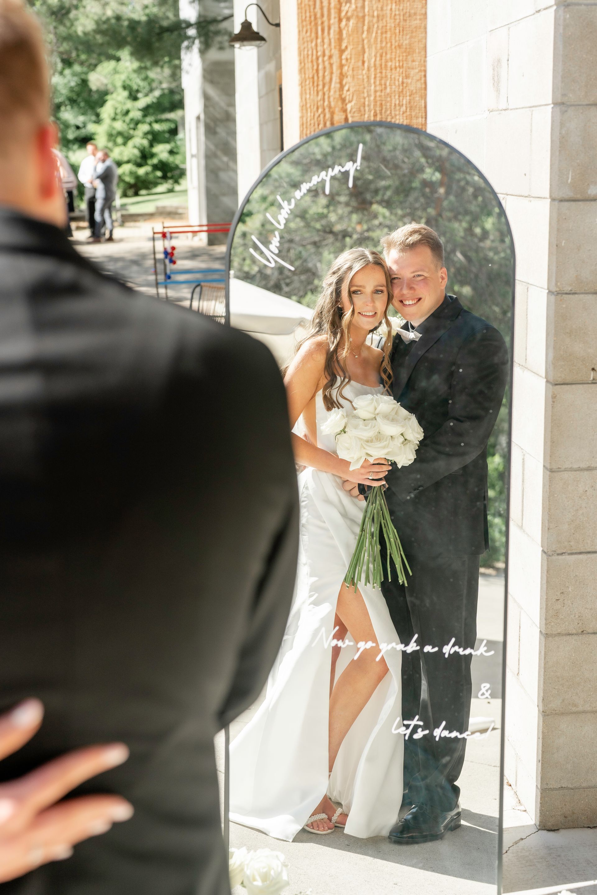 A man is taking a picture of a bride and groom in front of a mirror.