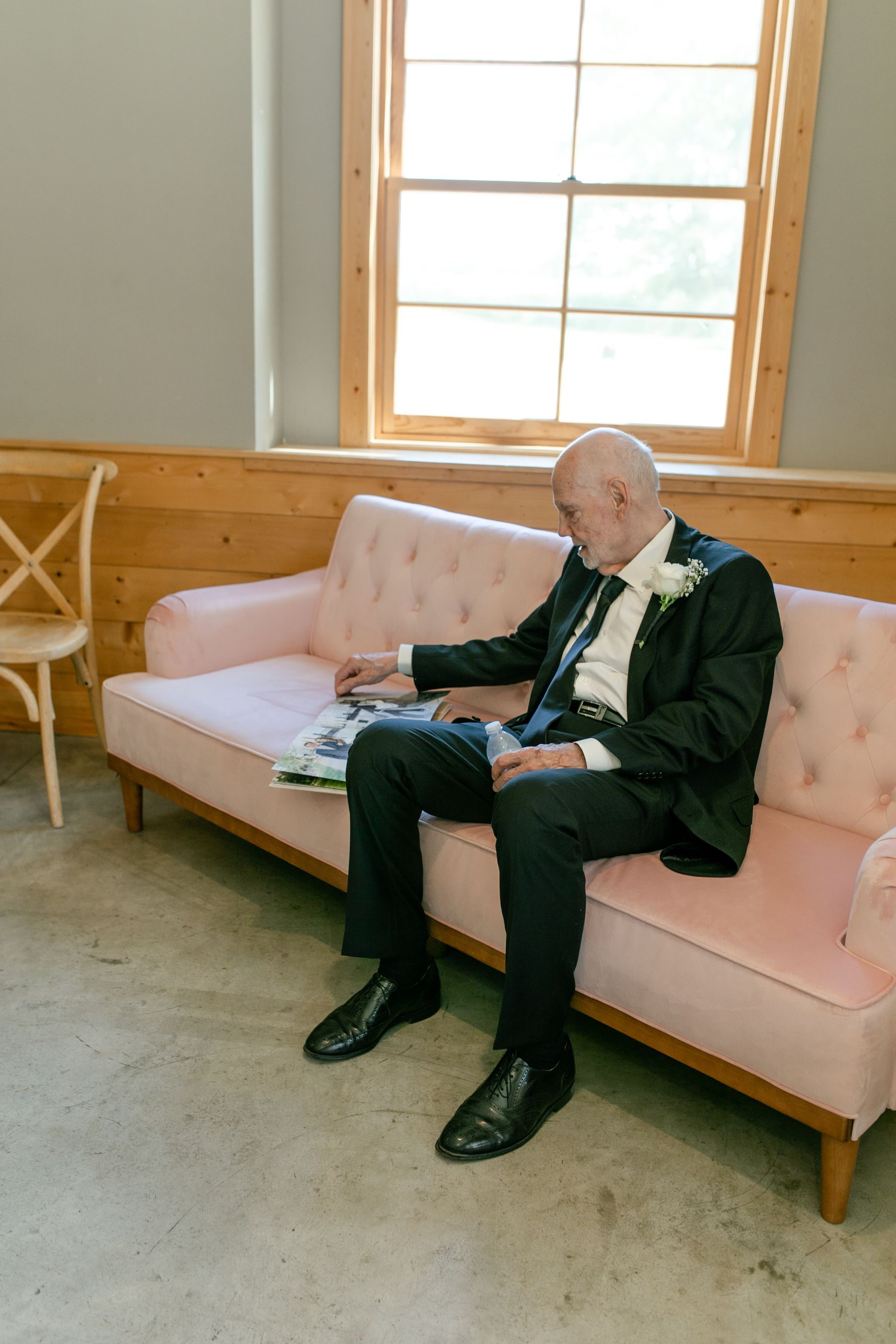 A man in a suit and tie is sitting on a pink couch.