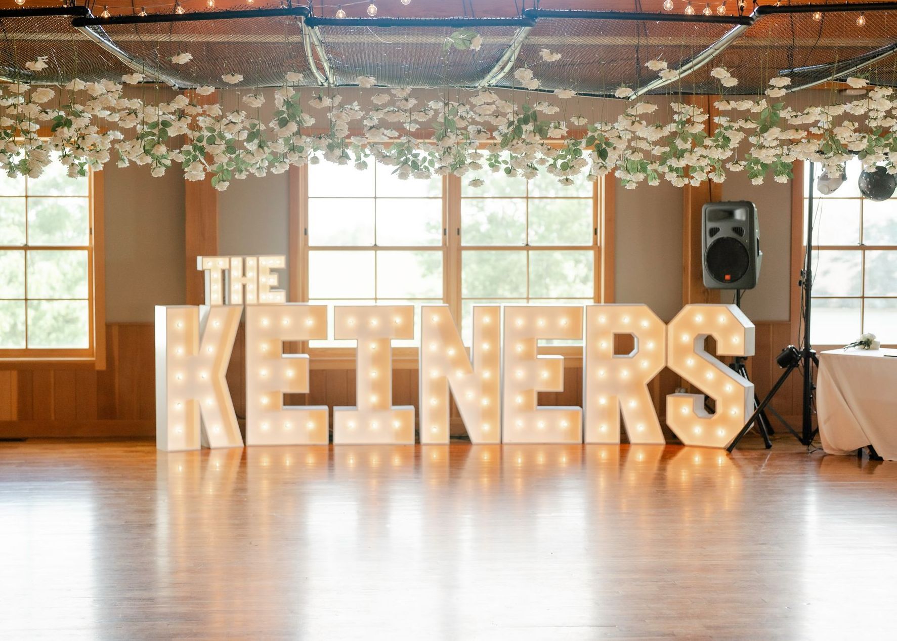A large lighted sign that says `` the keiners '' is sitting on a wooden floor in a room.