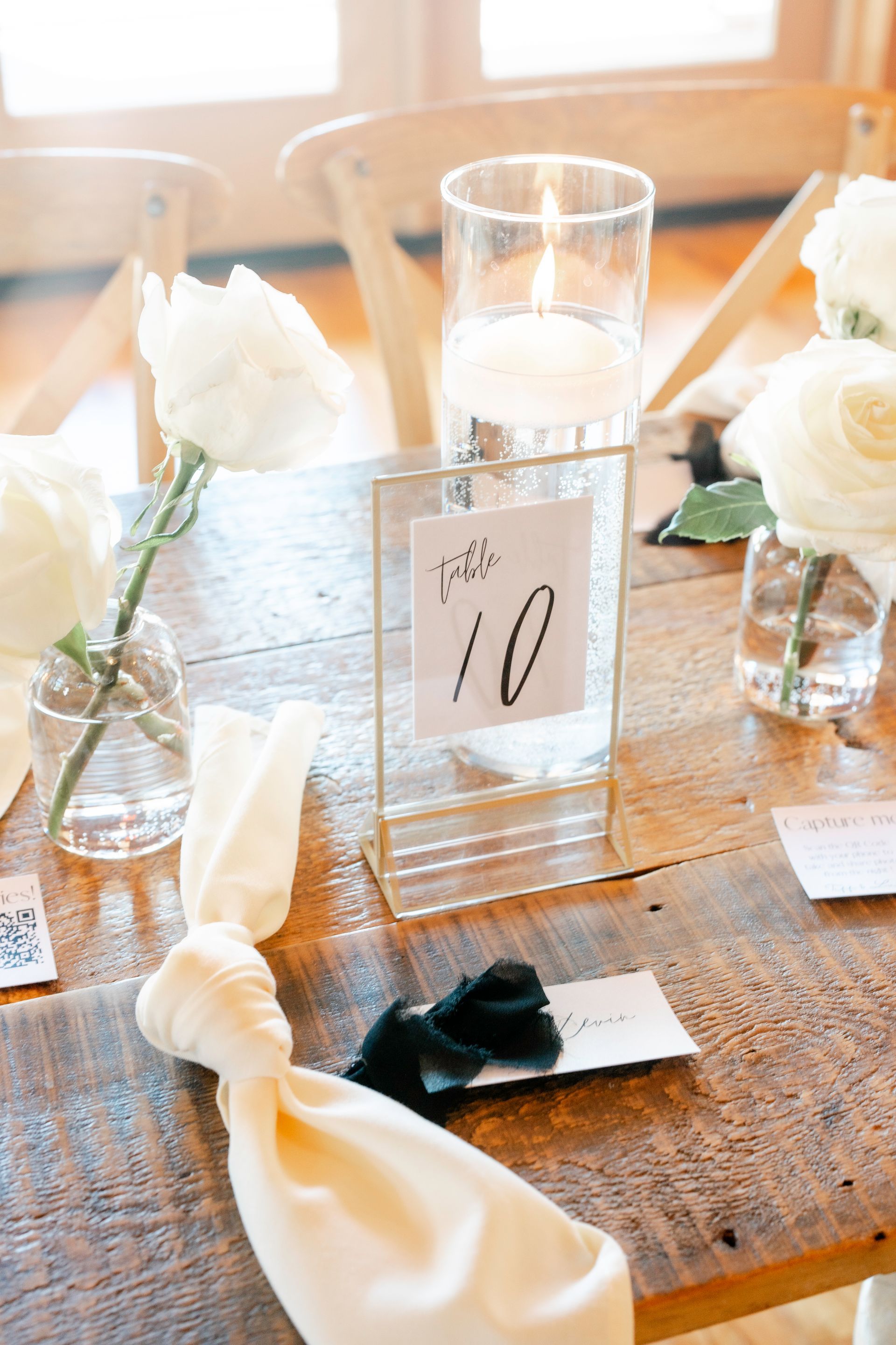 A wooden table with a table number and candles on it.