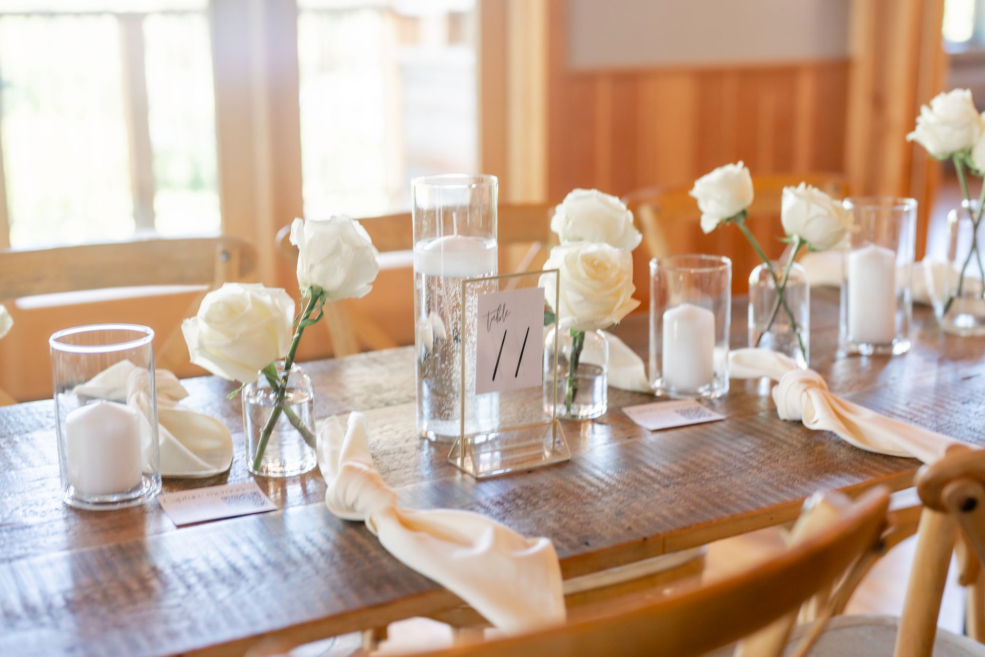 A long table with flowers and candles on it in front of a wooden wall.