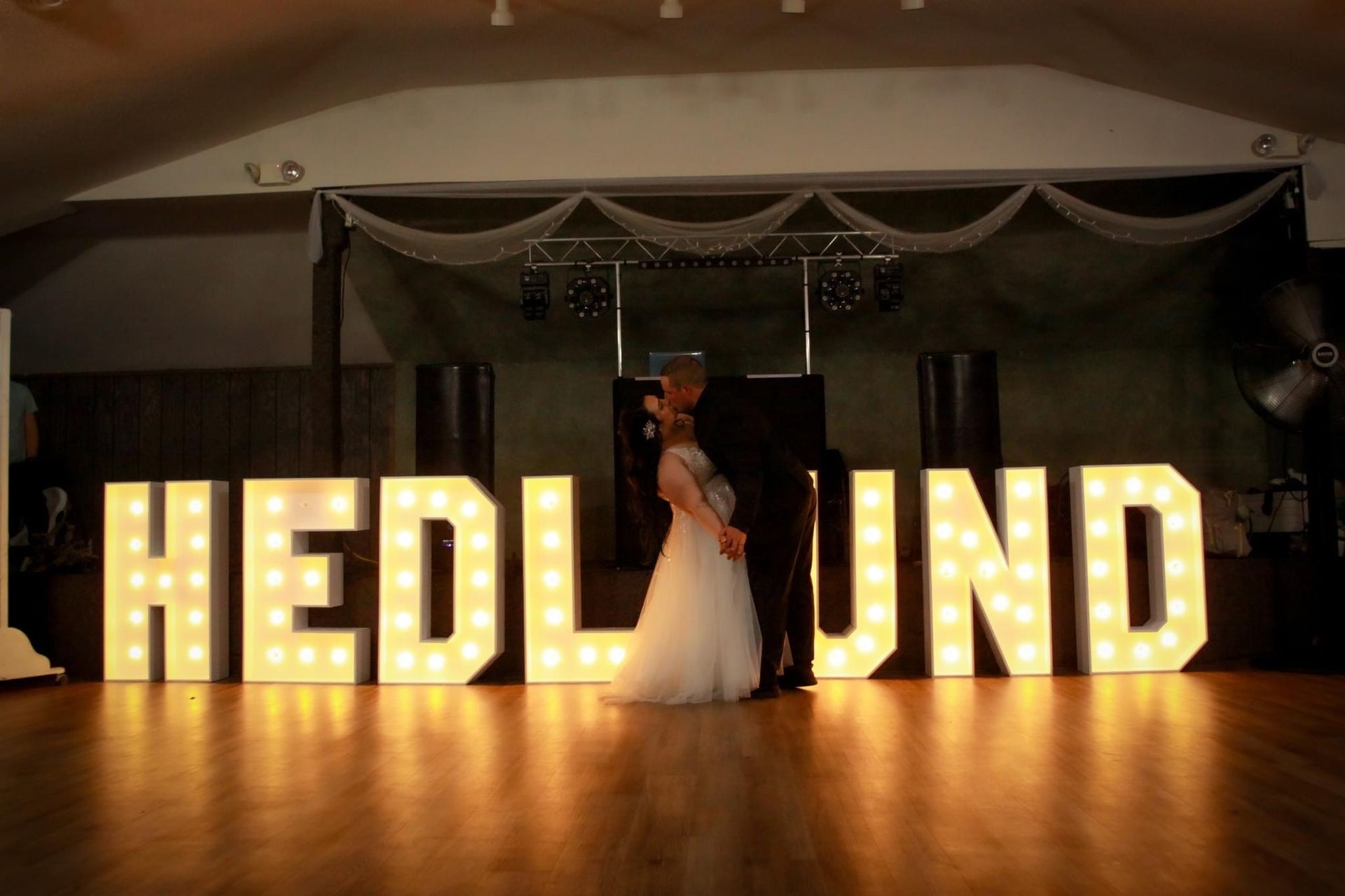 A bride and groom are dancing on a wooden dance floor.
