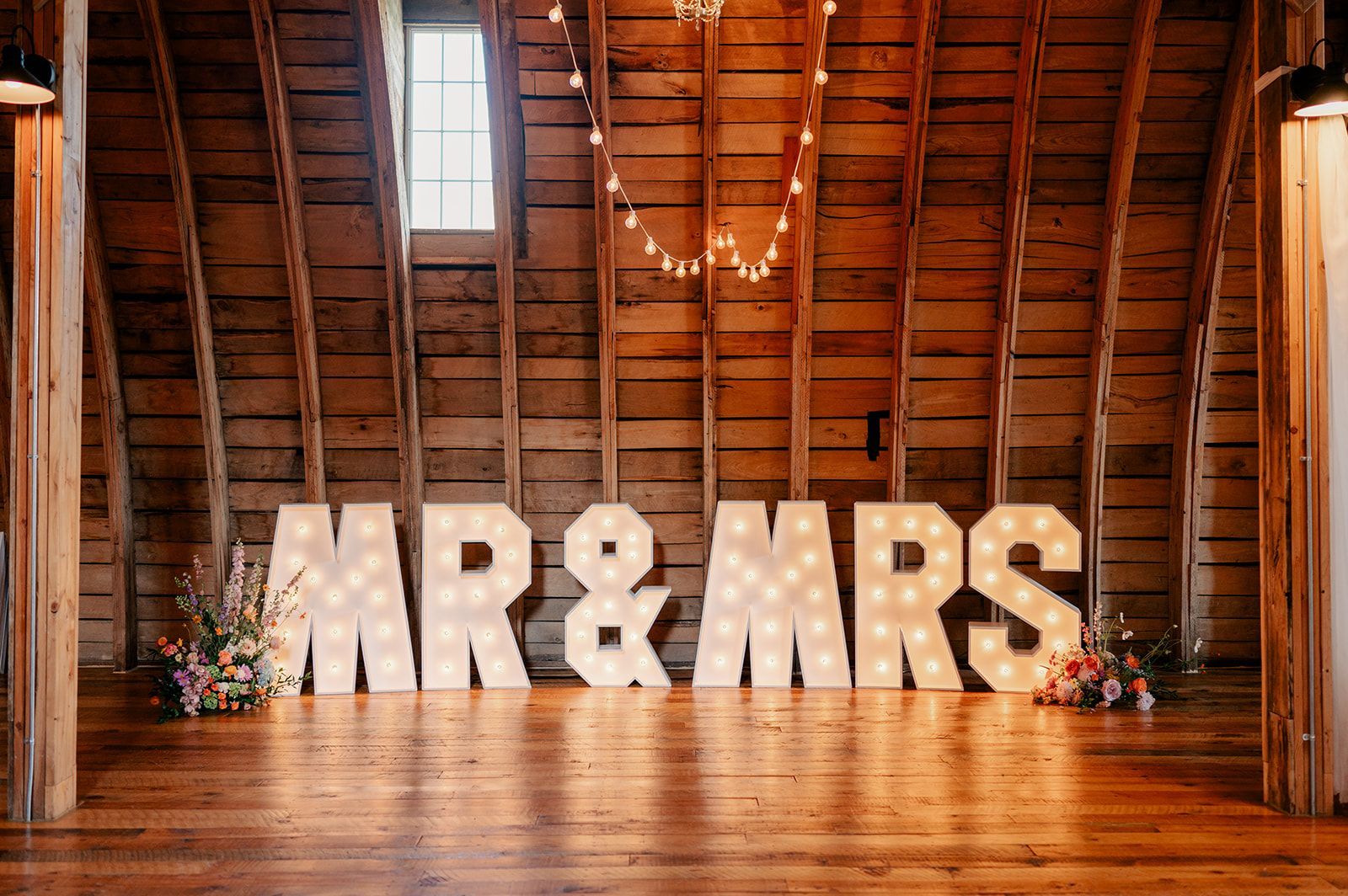 The letters mr and mrs are lit up in a barn.