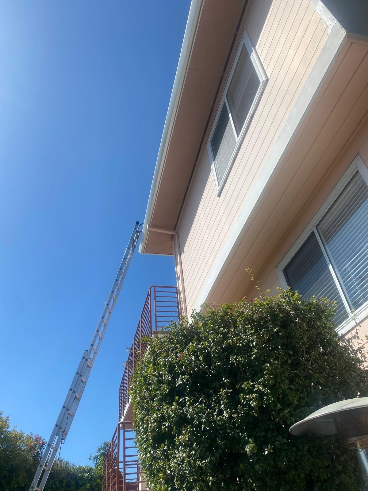 Apartment building with red exterior stairs and a ladder against the side under a clear blue sky