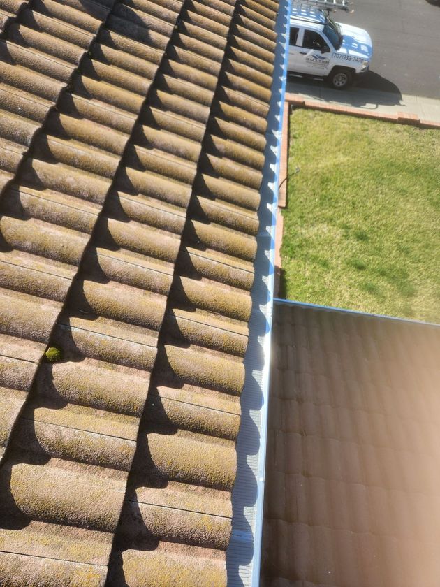 Roof tiles with a damaged edge and a view of a driveway and lawn below