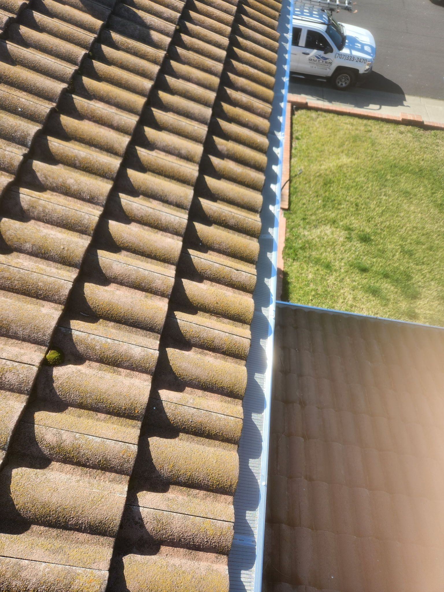 Roof tiles with a white van and green lawn in the background, plus a small inset of roof close-up