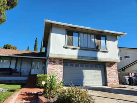 Two-story suburban house with a garage, brick and white siding, under a clear blue sky.