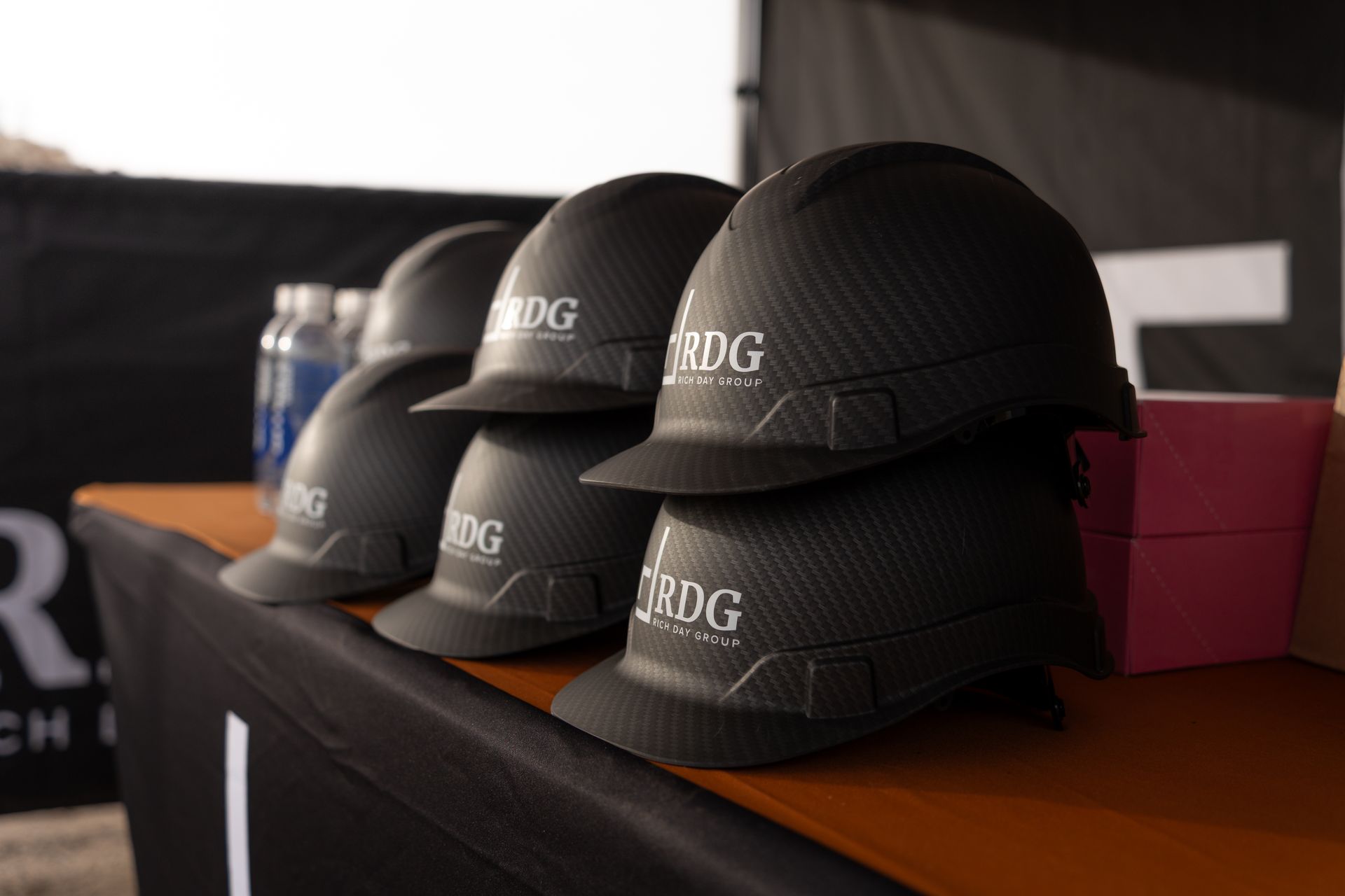 Black RDG-branded hardhats stacked on a table under an event tent.