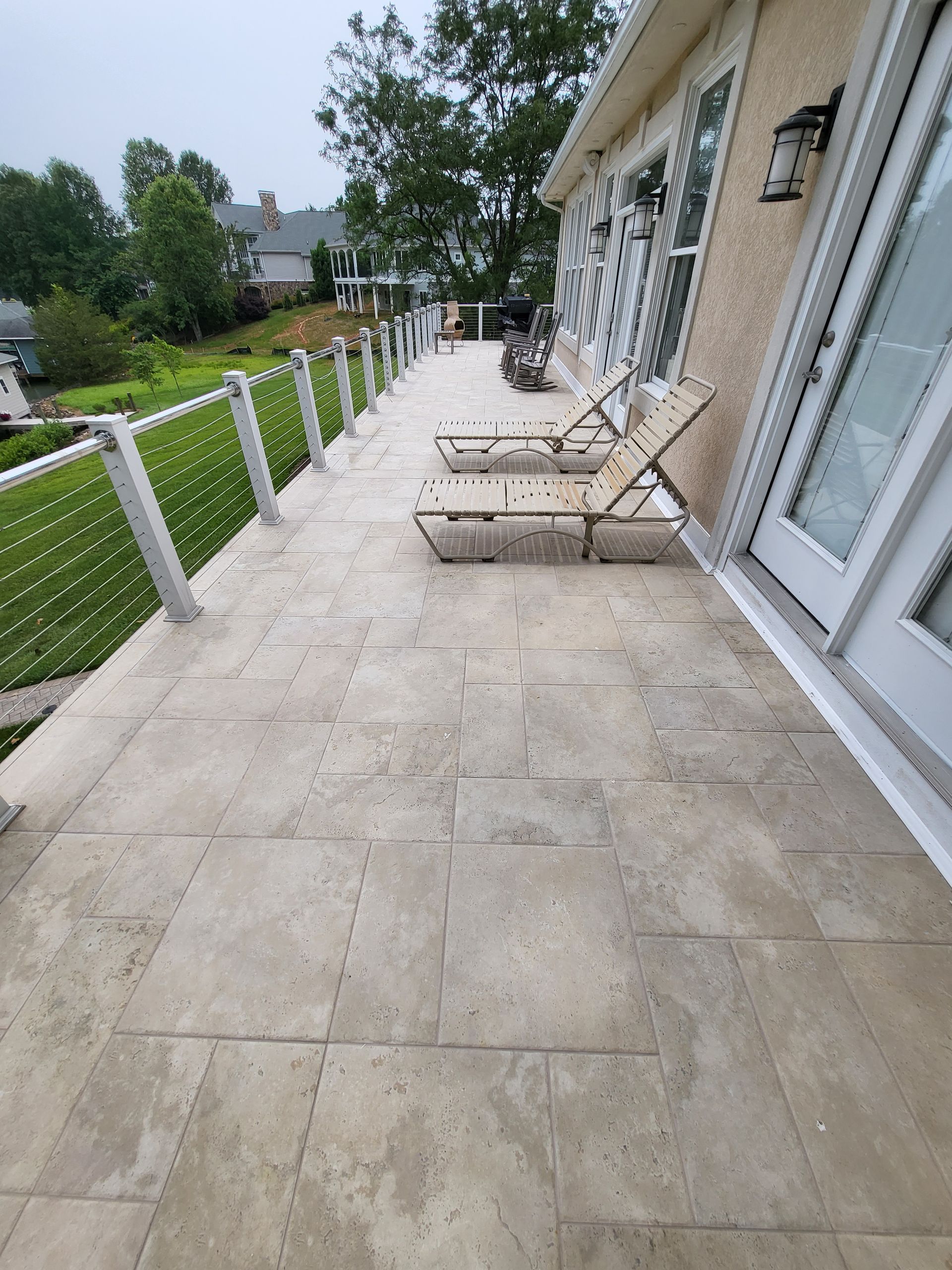 Stone patio beside a house with lounge chairs and a fenced garden path
