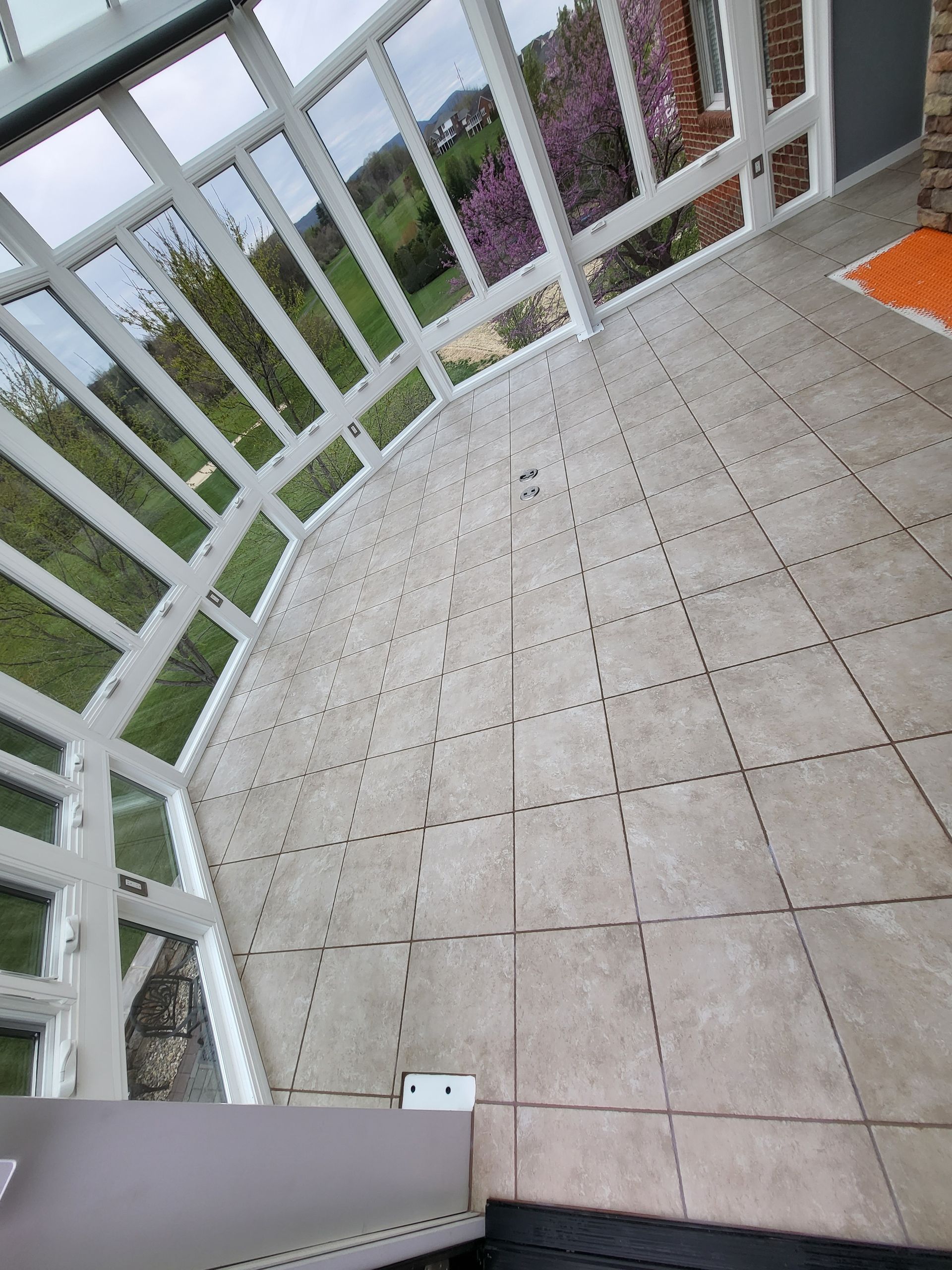 Curved white-railed balcony with beige tiled floor and orange chair in the corner
