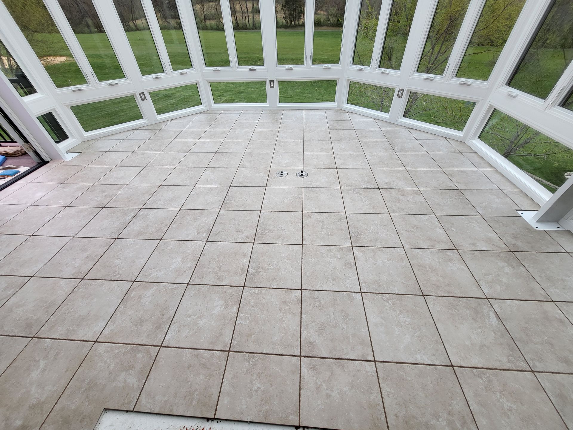 Tiled screened porch floor with white railing and green lawn beyond