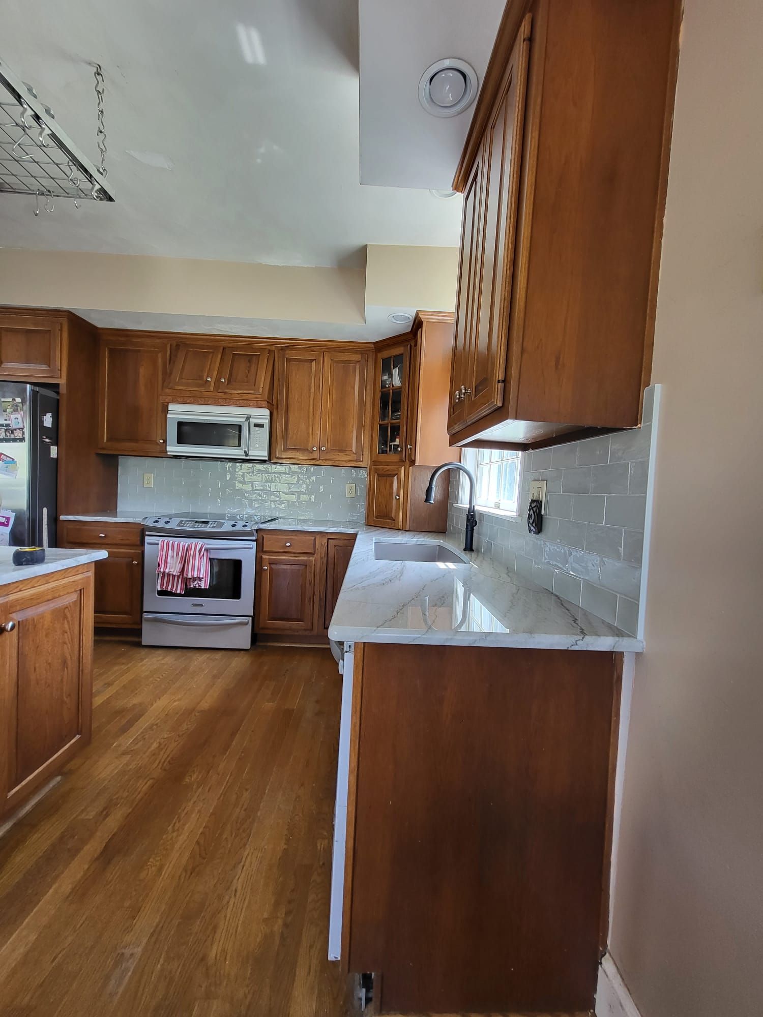 Wooden kitchen with cabinets, white countertops, stainless stove, and a microwave above the oven.