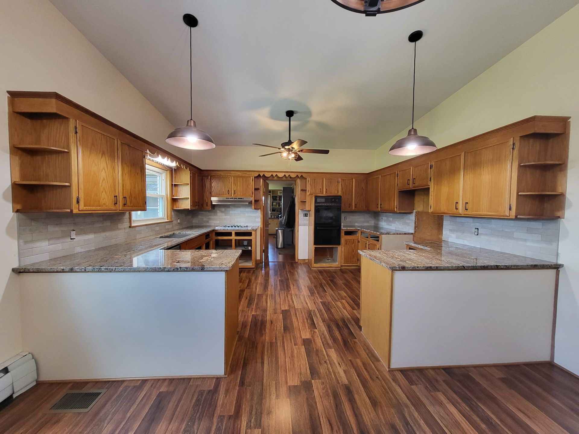 Spacious kitchen with granite counters, wood cabinets, pendant lights, and hardwood floors