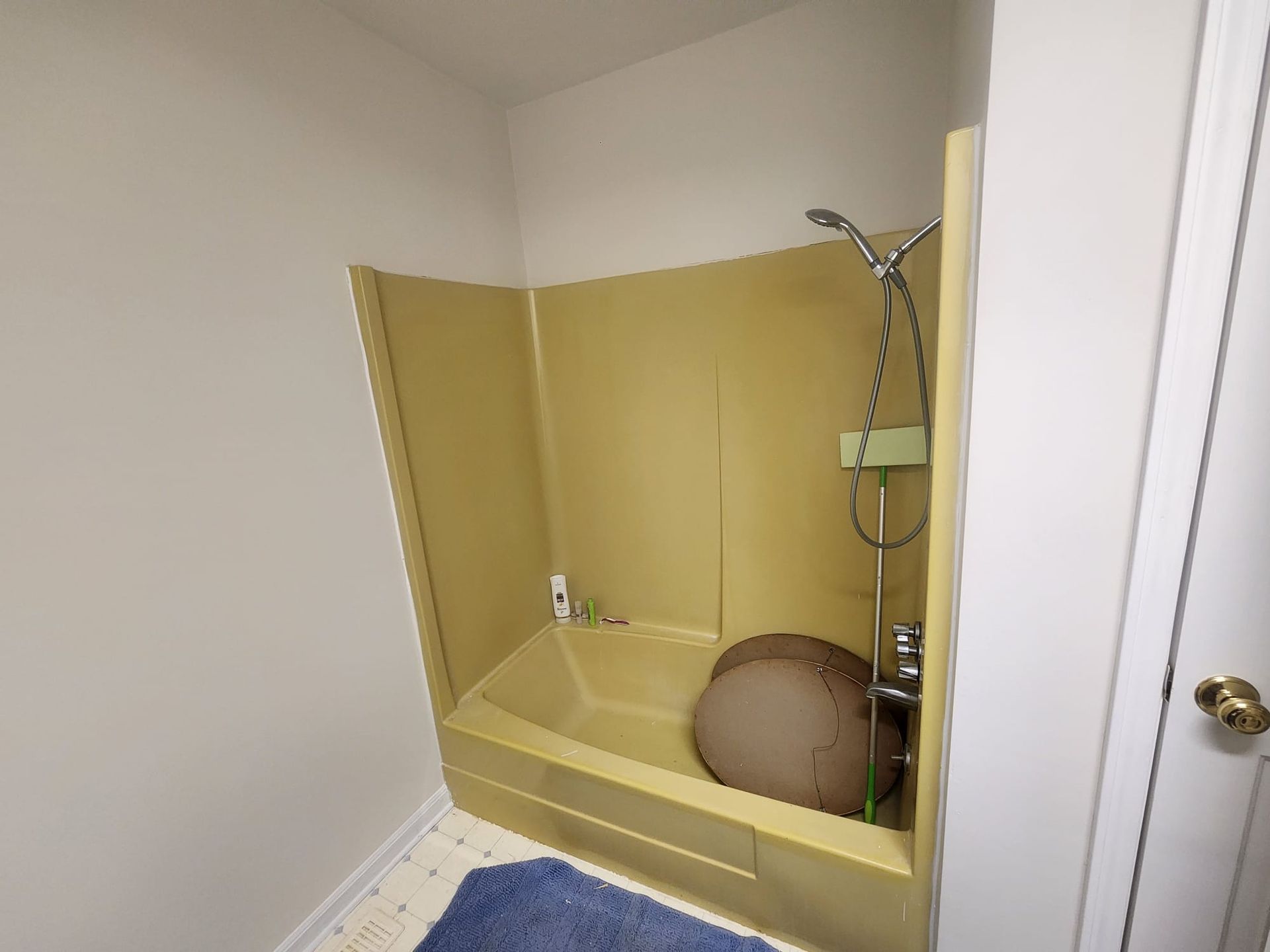 Yellow shower stall with a handheld showerhead in a small bathroom corner